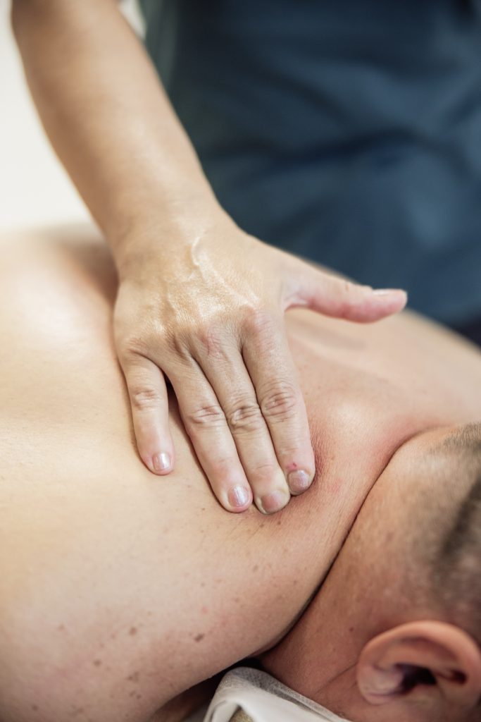 ruka certifikovanej masérky tlačí na chrbát klienta pri reflexnej masáži